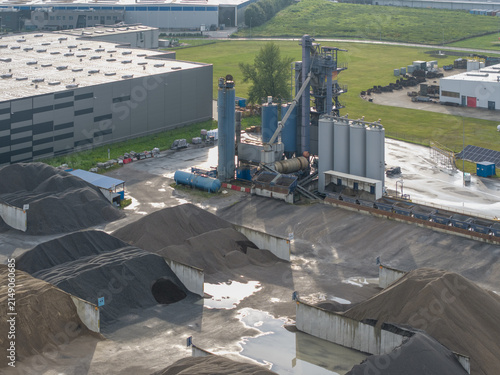 Aerial view of the bituminous mass plant featuring industrial silos, machinery, and large piles of aggregate materials stored in concrete bays in Skawina, Lesser Poland Voivode, Poland.