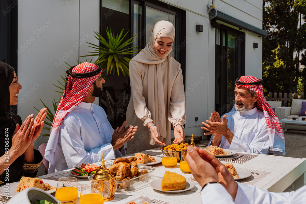 Fototapeta premium Muslim family members enjoying a traditional meal outdoors