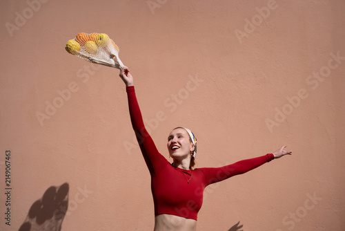 Fashionable woman holds citrus fruit in mesh bag