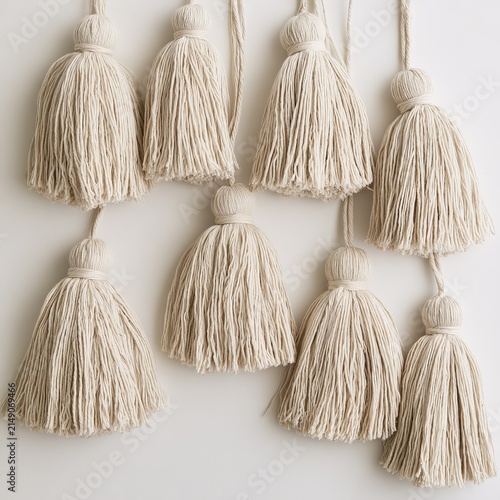 Beige cotton tassels appear on white surfaces.