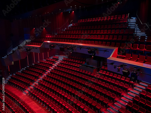 Fotografie Empty red seats and a technical lighting bridge in a multi level theater auditorium with dramatic red and blue lighting, concert hall