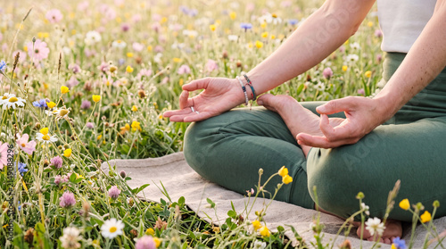 Person meditates cross legged among colorful wildflowers in a summer meadow