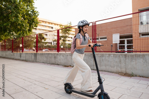 Young woman commuting on electric scooter to school