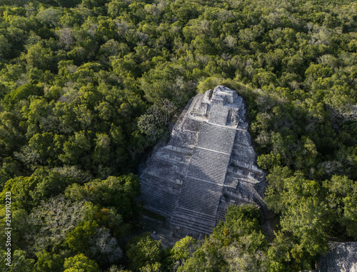 Aerial view of the ancient Mayan pyramid of Becan rising above the dense tropical jungle canopy in Calakmul, Campeche, Mexico.