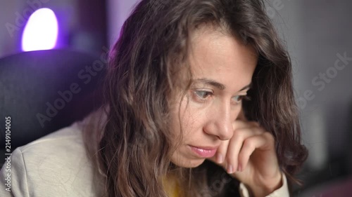 Stressed and pensive woman thinking about problems while working on a computer at night with purple led lights in background