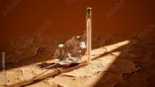 Thermometer standing in cracked dry soil under intense sunlight. Extreme heat, drought, climate change, global warming, water shortage and environmental crisis concept.