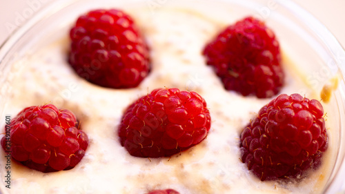Cottage cheese dessert with raspberries in a clear cup. Macro shot.