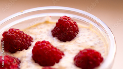 Cottage cheese dessert with raspberries in a clear cup. Macro shot.