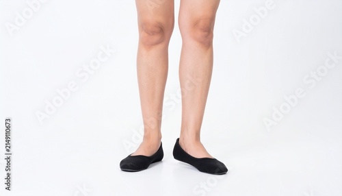 Closeup of a womans legs wearing black ballet flats isolated on white background