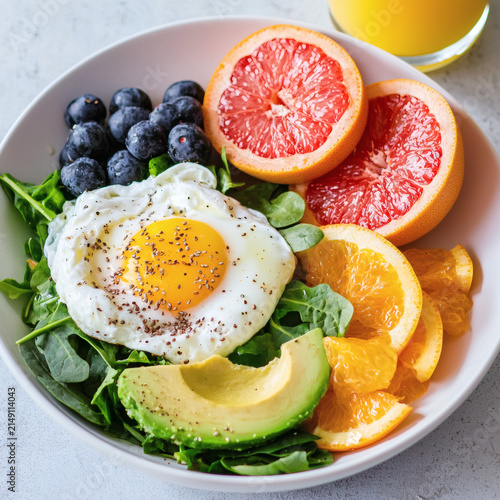 Healthy breakfast bowl featuring fresh fruits avocado spinach and a fried egg for nutritious start to the day