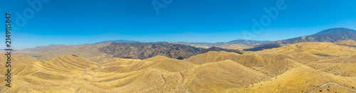 Aerial view of the Caliente Fish Fire burn area showing scorched earth and dry golden rolling hills under a clear blue sky in Caliente, CA, United States.