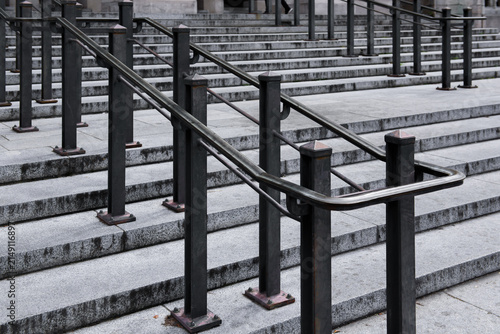 Black metal handrail with sturdy posts mounted along stone steps, featuring a clean and functional design commonly found in commercial and public architecture.