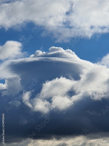 Bild auf Leinwand Rare pileus cloud forming a smooth cap over a developing cumulonimbus thunderstorm cloud against a blue sky