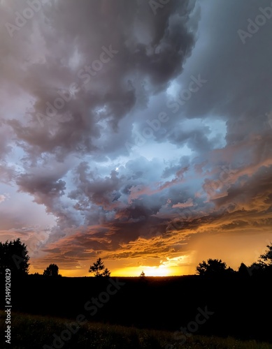 Dramatic sunset sky with soft clouds over distant hills.