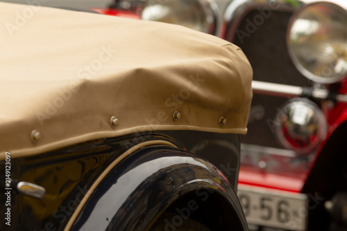 Canvastavla Tight view of a glossy black fender and beige canvas convertible hood on a vintage car, with metal fasteners and seam details visible