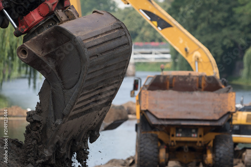 EXCAVATOR AND ARTICULATED HAULER - Construction machines are working on the river
