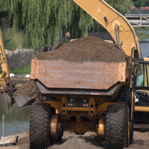 EXCAVATOR AND ARTICULATED HAULER - Construction machines are working on the river
