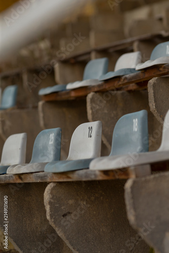 Принти на полотні Close-up view of numbered molded plastic seats mounted on weathered concrete bleacher steps in an outdoor stadium