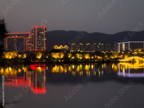 Obraz na plátně Captivating Urban Nightscape with Vibrant Lights and Mirror-Like Reflections