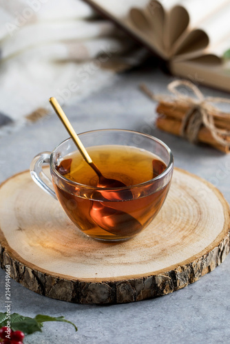 Homemade herbal tea in glass cup with wooden spoon on rustic wood slice