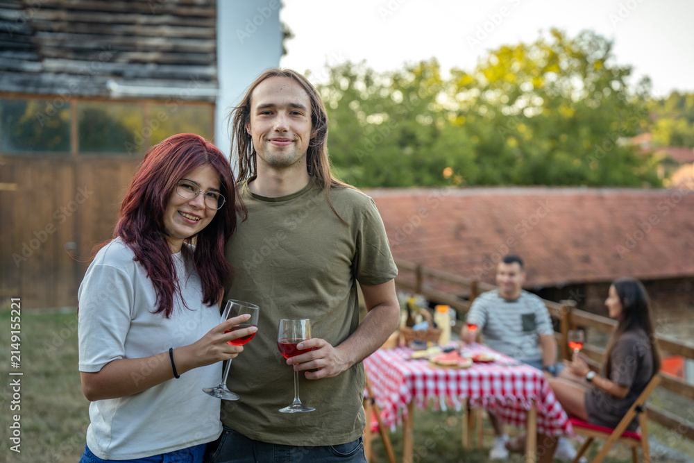 Obraz premium Happy young couple enjoying red wine at outdoor social gathering