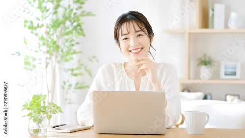 自宅のデスクでノートパソコンに向かいとびきりの笑顔を見せる女性