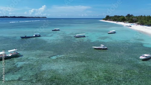 Aerial view of boats floating on pristine turquoise water near a white sandy beach in indonesia