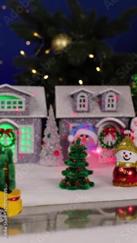 Against the backdrop of a Christmas village, an unusual Santa Claus and a yellow car with a Christmas tree on the roof drive by