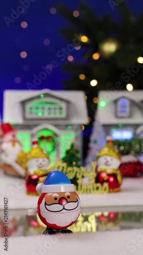 An unusual Santa Claus appears in front of a Christmas village