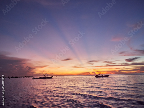 Foto Boats on ocean at tropical sunset with crepuscular rays