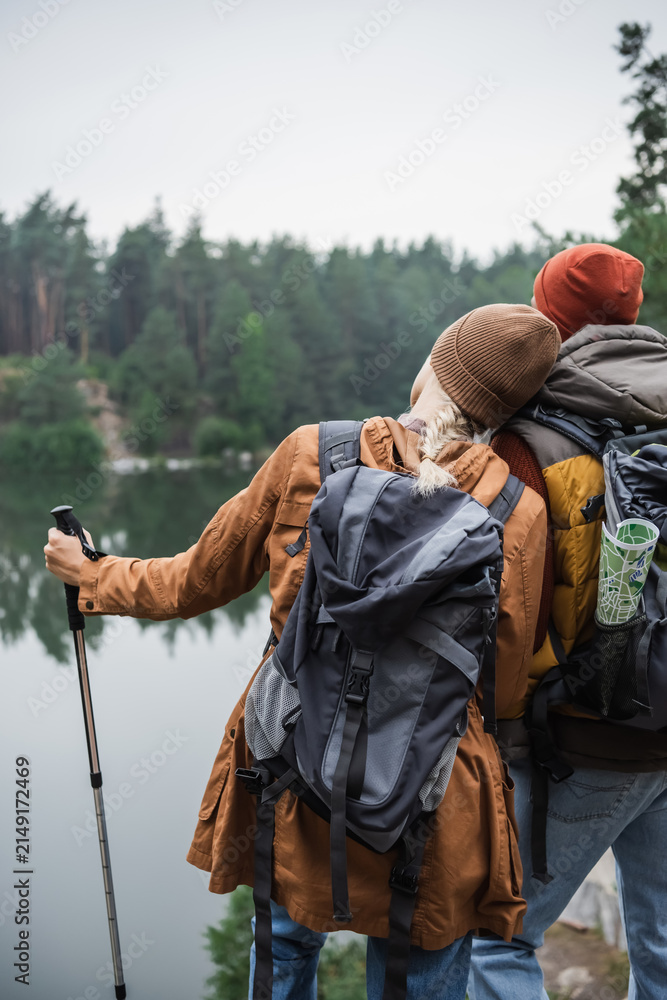 Fototapeta premium Couple enjoys a peaceful hike in a vibrant autumn forest by a tranquil lake