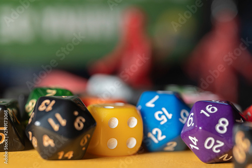 Obraz na plátně Row of colorful polyhedral dice with blurred meeple figures in background The Co