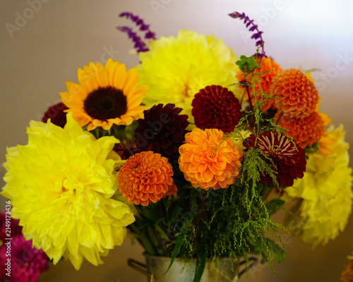Bright flower arrangement in a vase with sunflowers and dahlias in an indoor setting