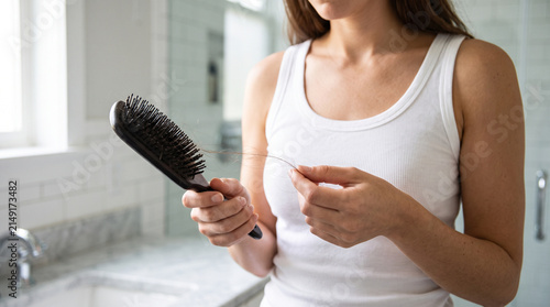 Woman detangling long hair with wooden brush, symbolizing hair health, grooming, self care, beauty treatment, and daily hygiene routine.