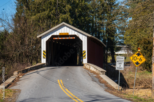 Old covered bridge located on a rural road surrounded by trees in the daytime