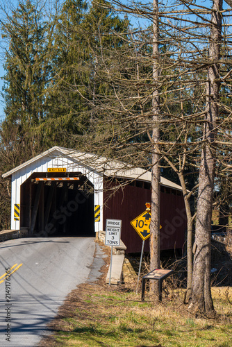 Old covered bridge located on a rural road surrounded by trees in the daytime