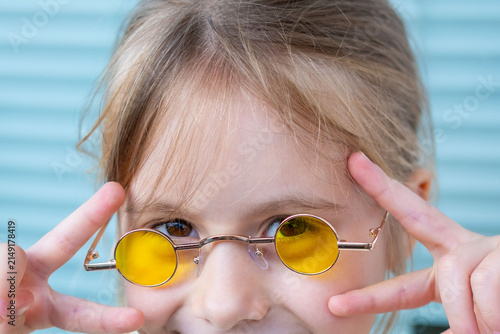 Obraz na płótnie little clever girl yellow round sunglasses, funny facial expression, smart profe