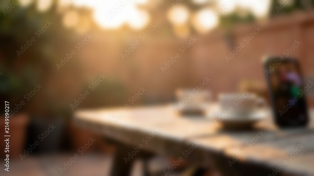 Fototapeta premium Blurred smartphone on sunlit outdoor table for mobile banking app