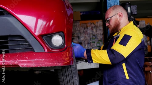 Focused automotive mechanic repairing vehicle wheel showing professional concentration workshop, professional car technician inspecting