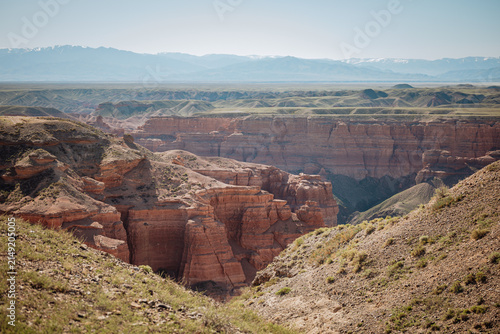 Panoramic view of Charyn Canyon with dramatic red cliffs and a deep gorge captured in natural daylight from a scenic viewpoint. Perfect for travel, tourism and nature campaigns, with useful copy space
