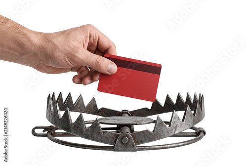 Hand holding a red credit card over a steel animal trap