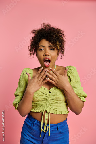 Canvas Print Joyful expression of a young woman in vibrant attire against a playful pink back
