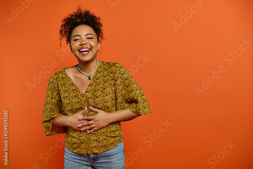 Fotografie Bright laughter of a young african american woman in vibrant attire against an o