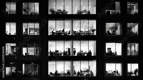 Office building facade at night with illuminated windows showing people