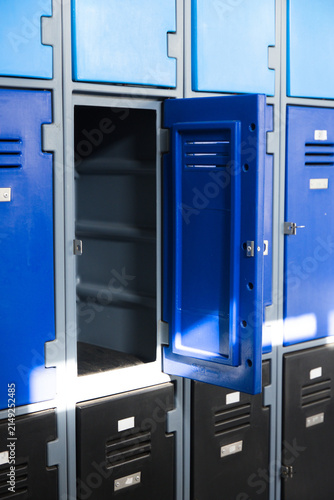 Open blue upper locker is revealing empty shelves on hall wall, with sunlight showing scuff marks