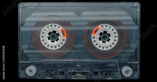 Vintage Audio Cassette with Spinning Reels. Transparent tape cassette with rotating reels on black background, evoking analog recording and retro technology.