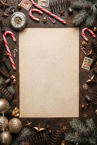 Blank parchment paper surrounded by christmas ornaments and vintage tools. Festive holiday background with candy cane, fir branch and antique clock. Steampunk style greeting card.