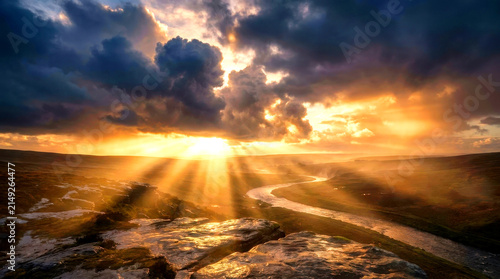 Golden Sunset Over Dramatic Cloudy Sky with Sun Rays and Winding River Landscape

