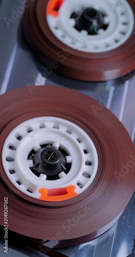 Spinning Audio Cassette Reels. Macro view of magnetic tape reels rotating inside a transparent cassette mechanism.