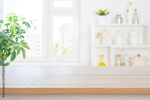 Empty kitchen table top with copy space on blurred interior and green houseplant background
